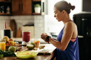 athletic woman slicing fruit while preparing smoothie in the kitchen.